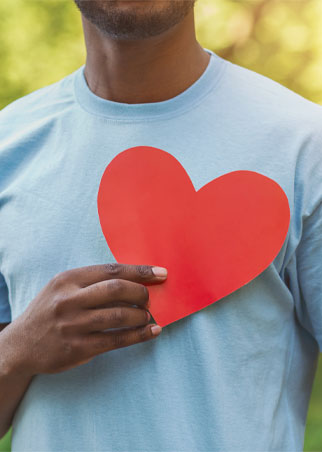 Man holding red paper heart on his chest