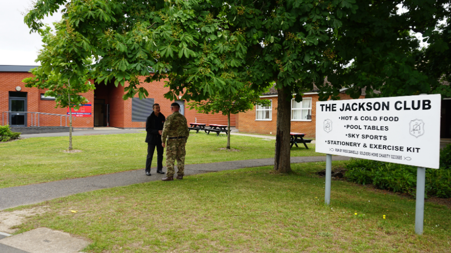 ASR Mike Blackstock outside the Jackson Club talking to a soldier with the Jackson Club sign on the left