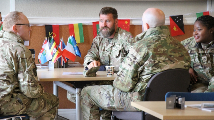 ASR Gerhard Olivier and ASR Peter Woodward speak to two soldiers around a table.